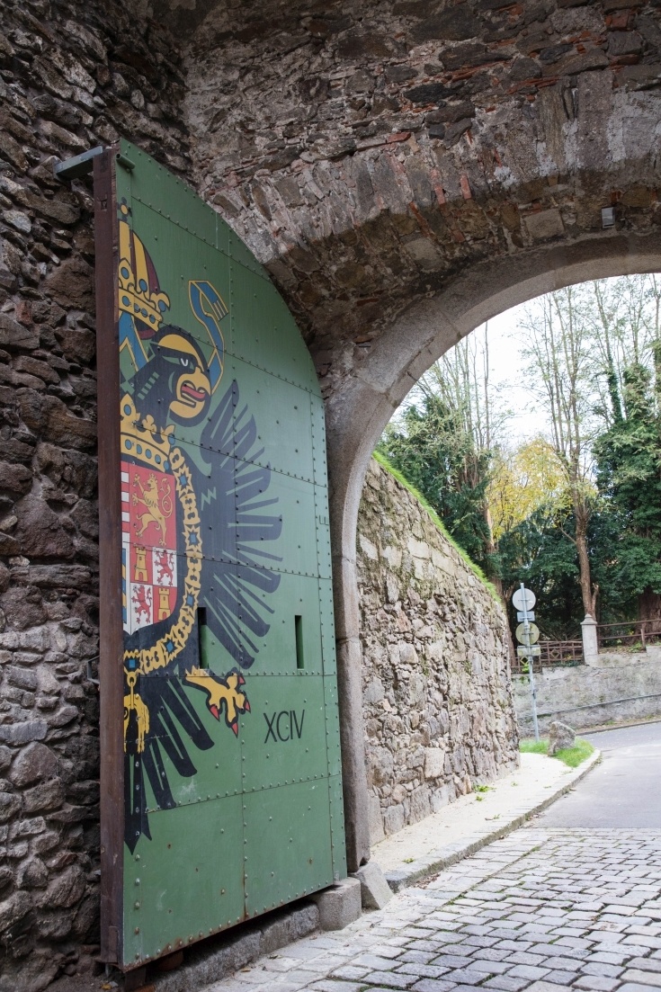 A stone archway filled with a half door painted green with an eagle on it.
